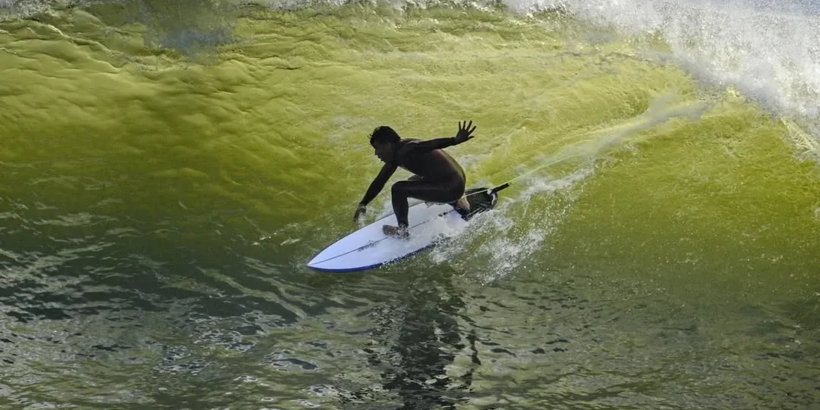Surfista numa onda verde, fotografado da areia pela BAD SURF PHOTO